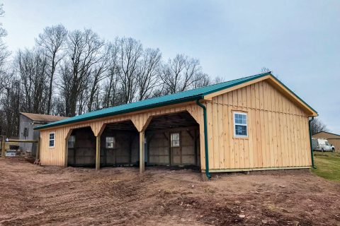 Open horse barn with 3 openings, light-colored wood siding, teal trim, and a teal roof.