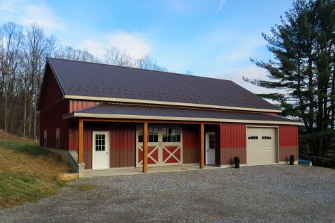 Large red and brown horse barn with overhang